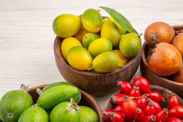 Vista frontale diversi frutti freschi all'interno di piastre su sfondo bianco colore tropicale vita sana bacche esotiche mature