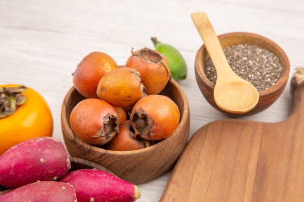 Vista frontale diversi frutti freschi all'interno di piastre su sfondo bianco tropicale colore maturo dieta esotico dolce