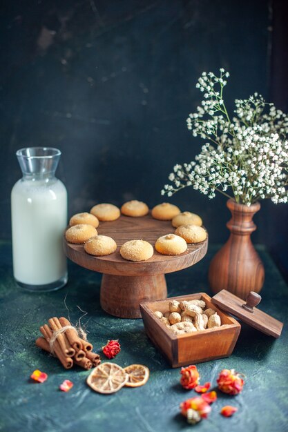 Vista frontale dolci deliziosi biscotti con latte e noci sulla superficie blu scuro