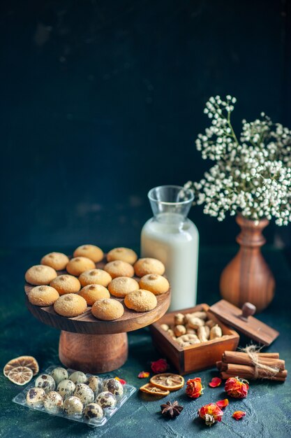 Vista frontale dolci deliziosi biscotti con latte e noci sulla superficie blu scuro