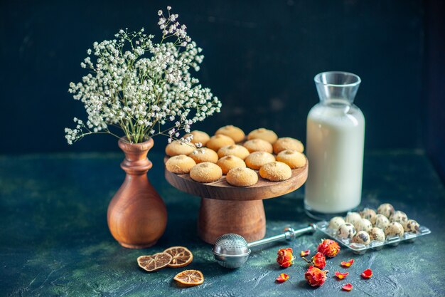 Vista frontale dolci deliziosi biscotti con latte e noci sulla superficie blu scuro