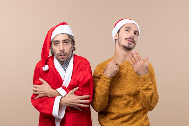 Vista frontale due ragazzi di natale uno con il cappotto della Santa che è freddo e l'altro che è caldo su fondo isolato beige