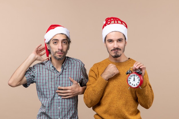 Vista frontale due uomini di natale uno che mette la mano al petto e l'altro che tiene una sveglia su fondo isolato