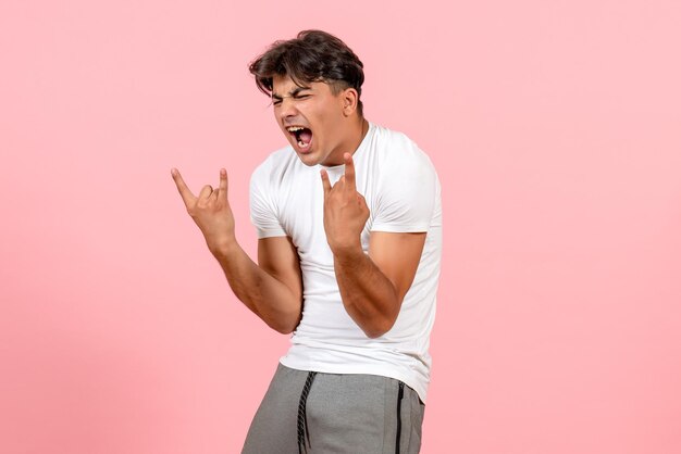 Vista frontale emotivo giovane maschio in t-shirt bianca su parete rosa colore modello emozione maschio