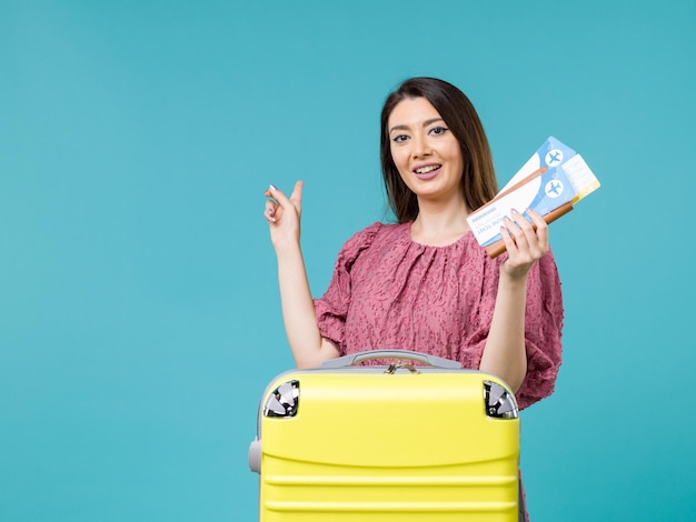 Vista frontale femminile in vacanza che tiene i suoi biglietti su sfondo azzurro viaggio viaggio estivo donna vacanza mare