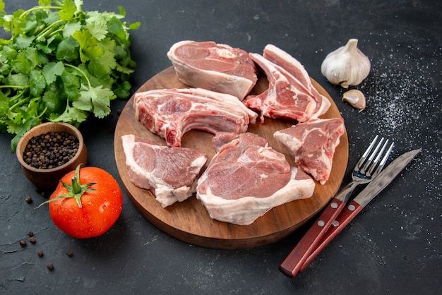 Vista frontale fette di carne fresca carne cruda con verdure e pomodori su sfondo scuro pasto da cucina cibo cibo per mucche piatto insalata barbecue animale