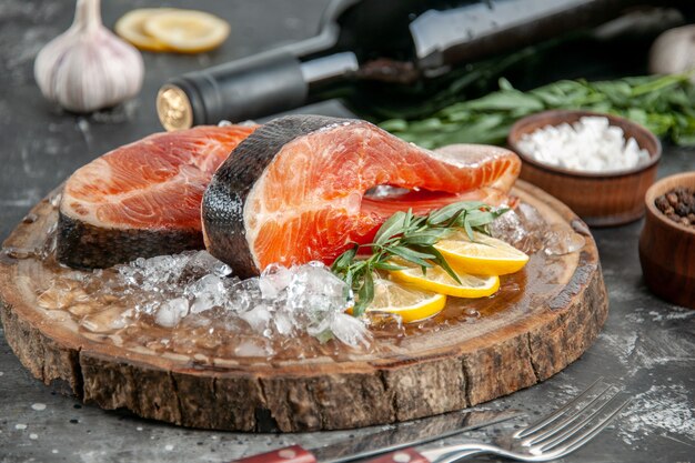 Vista frontale fette di pesce crudo con fette di limone e ghiaccio su barbecue grigio cibo carne foto pesce piatto colore colore