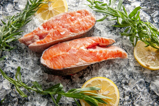 Vista frontale fette di pesce fresco con limone e ghiaccio su piatto di colore scuro carne cibo oscurità foto frutti di mare