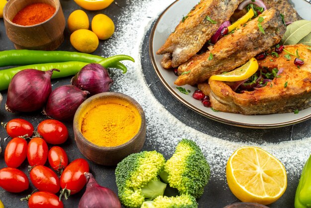 Vista frontale fette di pesce fritto con condimenti e verdure fresche su sfondo grigio colore dei frutti di mare cibo carne salute pasto insalata pepe