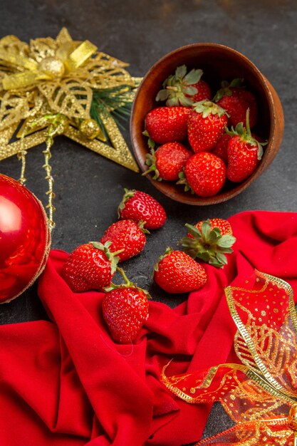 Vista frontale fragole rosse fresche all'interno del piatto su uno sfondo scuro colore della foto molti frutti morbidi