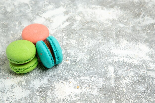 Vista frontale francese macarons torte colorate sulla superficie bianca torta torta cuocere il biscotto dolce biscotto