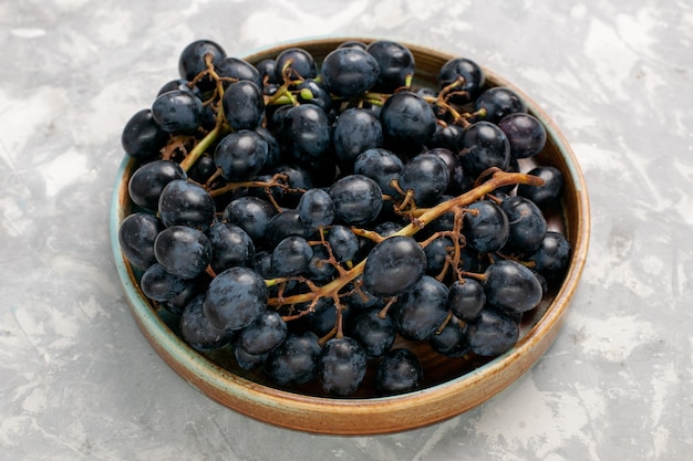 Vista frontale fresca uva nera succosa mellow dolce frutta sulla luce bianca scrivania frutta fresca mellow succo di vino