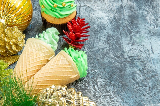 Vista frontale gelati albero di natale cupcake ornamenti di natale su grigio con posto libero