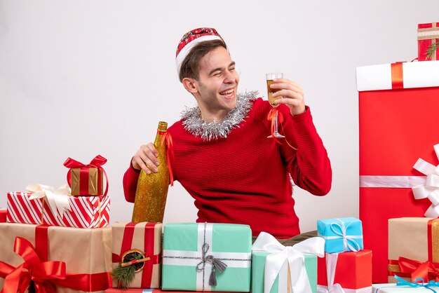 Vista frontale gioì giovane uomo seduto intorno a regali di Natale