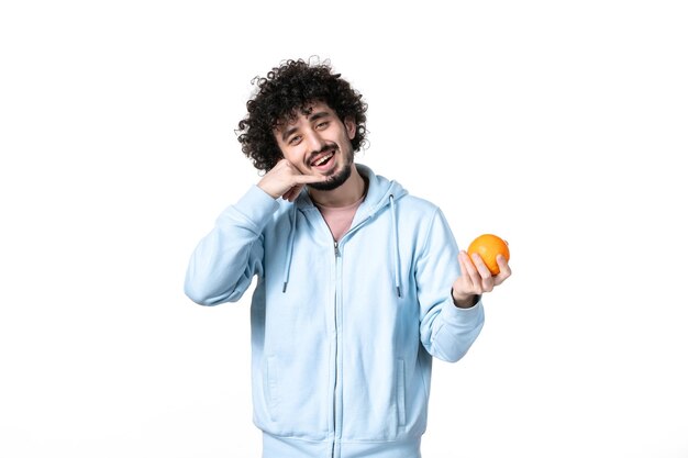 Vista frontale giovane che tiene arancia fresca su sfondo bianco salute del corpo muscolo che dimagrisce umano misurando peso perdendo frutta