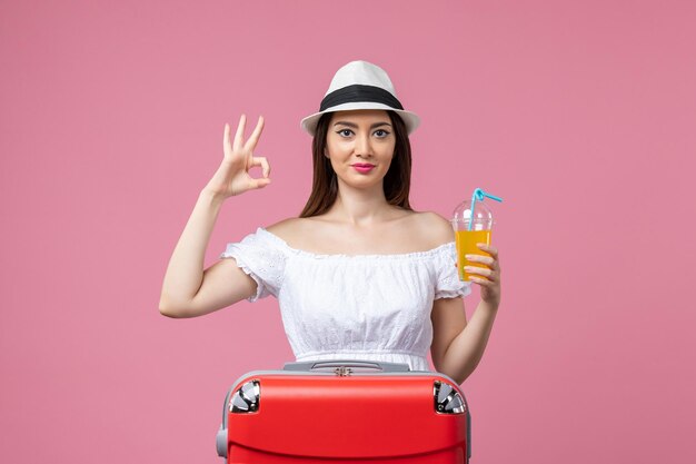 Vista frontale giovane donna che tiene cocktail durante le vacanze estive sul muro rosa emozione vacanza aereo viaggio viaggio estivo