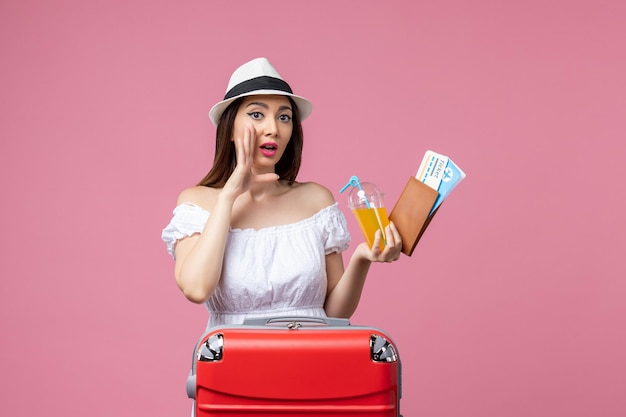 Vista frontale giovane donna che tiene i biglietti per le vacanze e posa sul muro rosa chiaro viaggio estivo emozione viaggio aereo