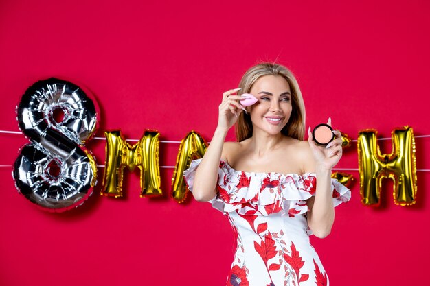 Vista frontale giovane donna che tiene scatola di polvere su rosso