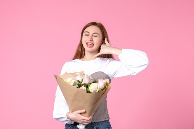 Vista frontale giovane donna che tiene un mazzo di belle rose sul rosa