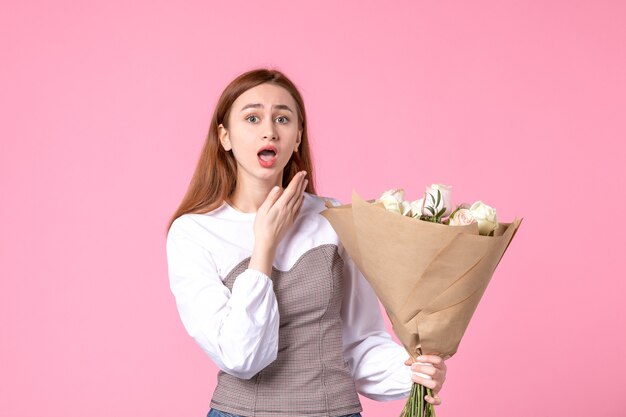 Vista frontale giovane donna che tiene un mazzo di belle rose sul rosa