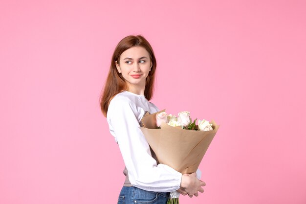 Vista frontale giovane donna che tiene un mazzo di belle rose sul rosa