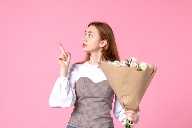 Vista frontale giovane donna che tiene un mazzo di belle rose sul rosa