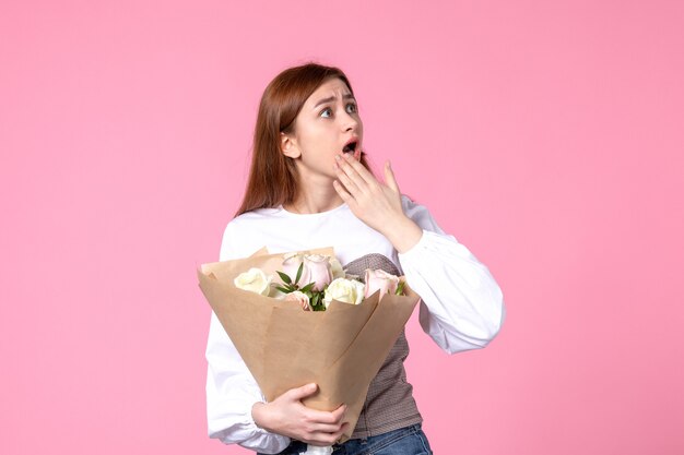 Vista frontale giovane donna che tiene un mazzo di belle rose sul rosa
