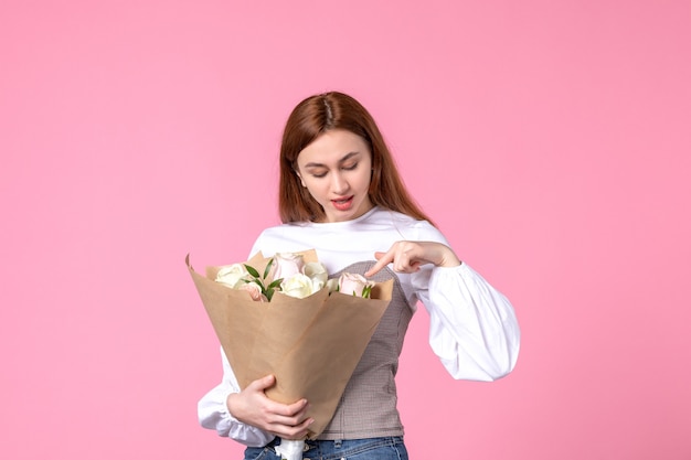 Vista frontale giovane donna che tiene un mazzo di bellissime rose sul profumo di marcia rosa