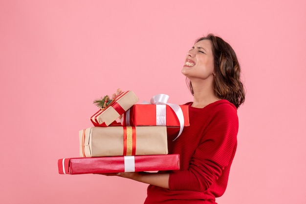 Vista frontale giovane donna che trasportano regali di Natale sul rosa