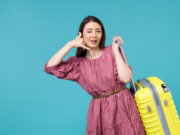 Vista frontale giovane donna che va in vacanza con la sua borsa gialla su sfondo azzurro viaggio viaggio estivo donna mare umano