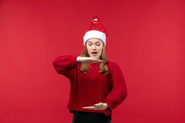 Vista frontale giovane donna con berretto rosso che mostra taglia, vacanze natale rosso