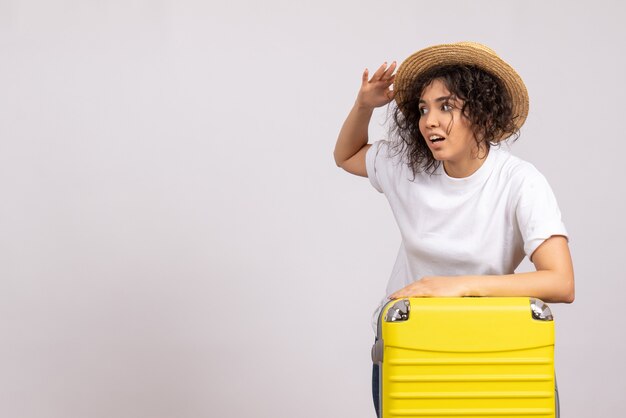 Vista frontale giovane donna con borsa gialla che si prepara per il viaggio su sfondo bianco colore vacanza volo aereo turistico resto voyage