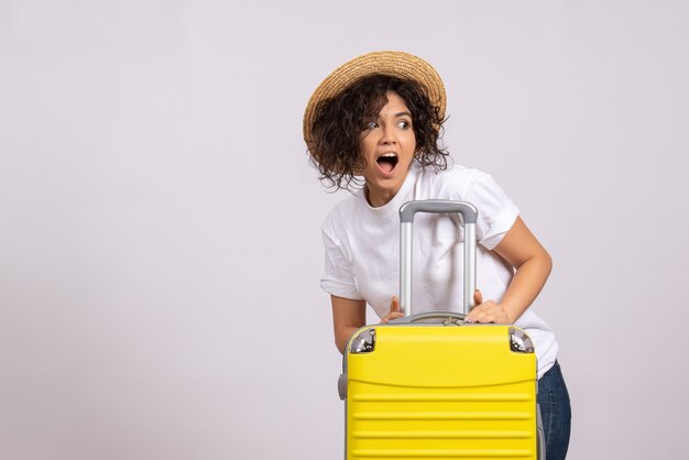 Vista frontale giovane donna con borsa gialla che si prepara per il viaggio su sfondo bianco vacanza turistica aereo viaggio colore resto