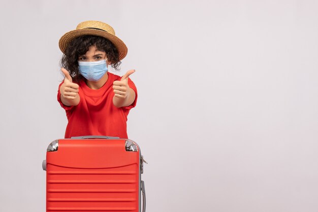 Vista frontale giovane donna con borsa in maschera su sfondo bianco colore covid- vacanza viaggio sole turistico virus