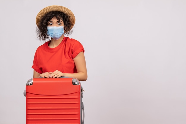 Vista frontale giovane donna con borsa in maschera su sfondo bianco colore covid- viaggio vacanza pandemia virus sole viaggio turista