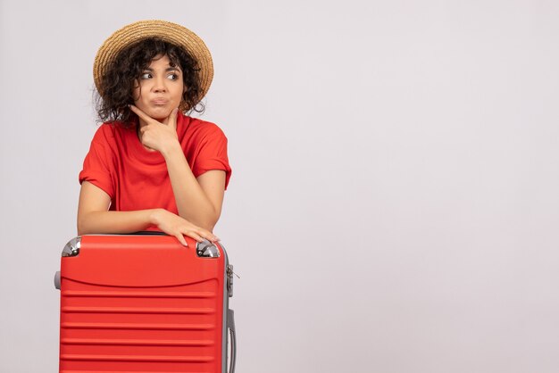 Vista frontale giovane donna con borsa rossa che si prepara per il viaggio su sfondo bianco colori volo aereo resto sole viaggio turistico vacanza