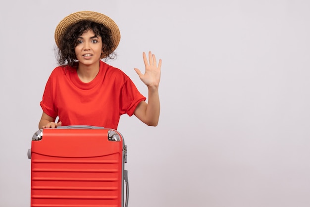 Vista frontale giovane donna con borsa rossa che si prepara per il viaggio sullo sfondo bianco vacanza colore sole viaggio resto volo turistico aereo