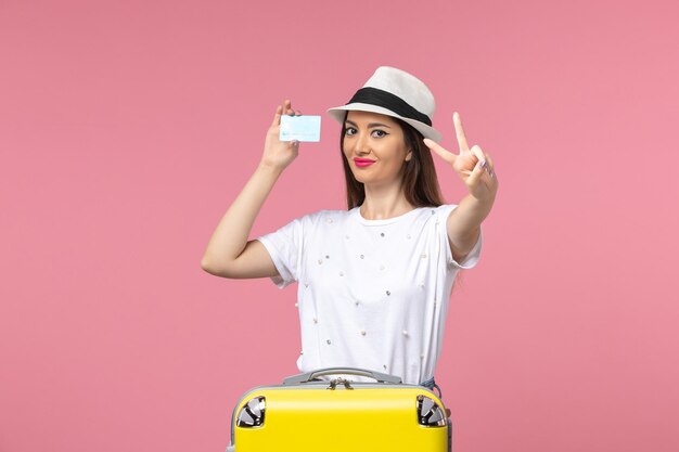 Vista frontale giovane donna con carta di credito bianca sul muro rosa viaggio estate emozione donna