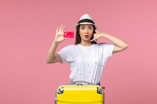 Vista frontale giovane donna con carta di credito rossa sul muro rosa viaggio estivo viaggio