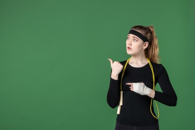 Vista frontale giovane donna con la fasciatura intorno al braccio ferito su sfondo verde atleta allenamento dolore salute donna lesioni corpo sportivo