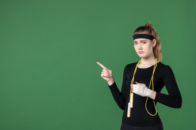 Vista frontale giovane donna con la fasciatura intorno al braccio ferito su sfondo verde atleta dolore salute lesioni corpo sportivo ospedale donna