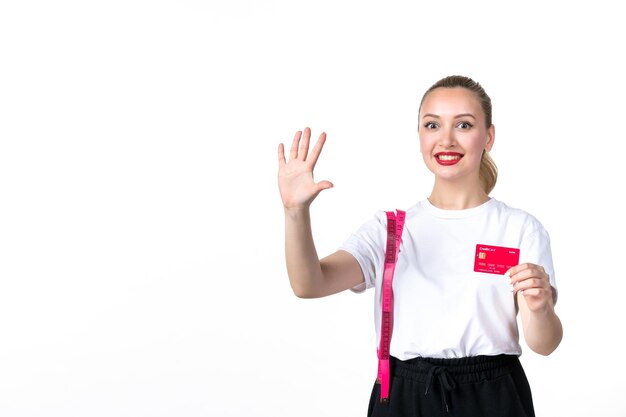 Vista frontale giovane donna con metro a nastro e carta di credito su sfondo bianco denaro perdente banca misurazione pelle corpo anca torso bellezza