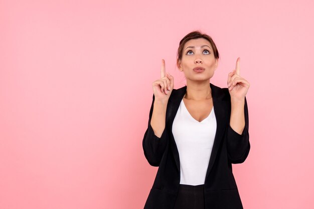 Vista frontale giovane donna graziosa in giacca scura su sfondo rosa