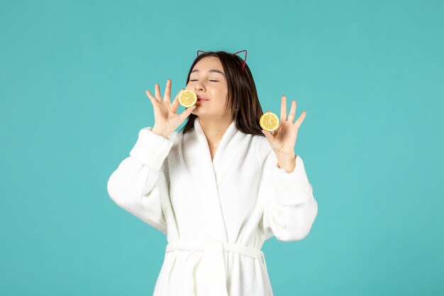 vista frontale giovane donna in accappatoio con limoni a fette su sfondo blu