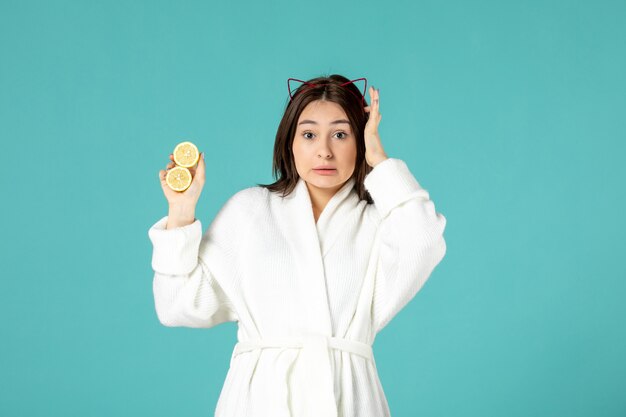 vista frontale giovane donna in accappatoio con limoni a fette su sfondo blu