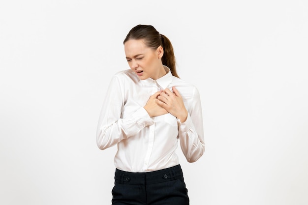 Vista frontale giovane donna in camicetta bianca che ha dolore al cuore su sfondo bianco lavoro d'ufficio modello di sentimento femminile emozione