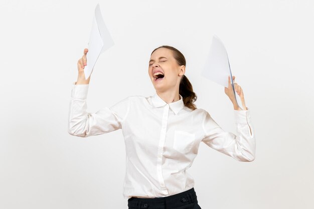 Vista frontale giovane donna in camicetta bianca che tiene documenti e si sente arrabbiata su sfondo bianco lavoro femminile emozioni sensazione ufficio