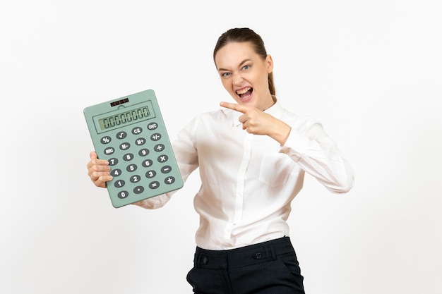 Vista frontale giovane donna in camicetta bianca che tiene grande calcolatrice su sfondo bianco lavoratore emozione femminile lavoro d'ufficio bianco