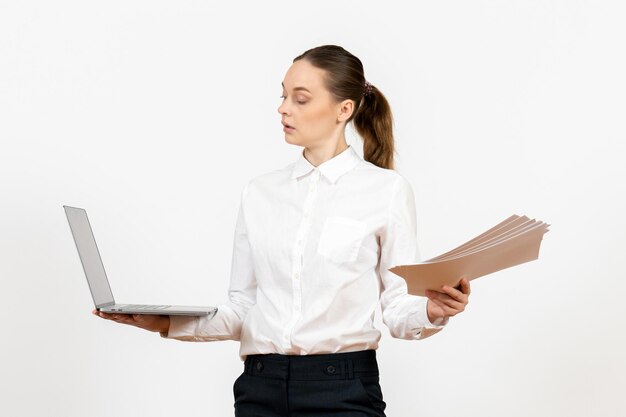 Vista frontale giovane donna in camicetta bianca che tiene laptop e documenti su sfondo bianco lavoro femminile ufficio emozione modello sentimento