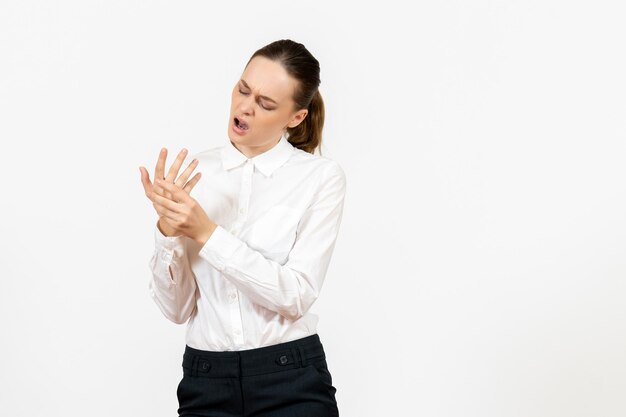 Vista frontale giovane donna in camicetta bianca con dolore al braccio su sfondo bianco lavoro d'ufficio emozioni femminili sensazione modello